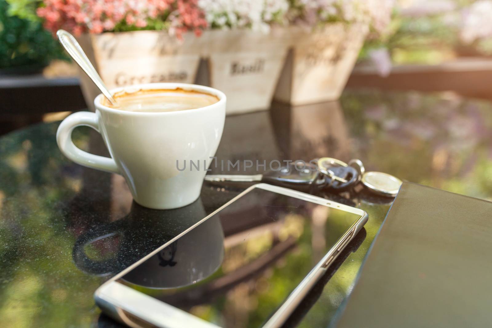 Digital smartphone and cup of coffee on desk with vintage flower. Simple coffee break in morning / selective focus
