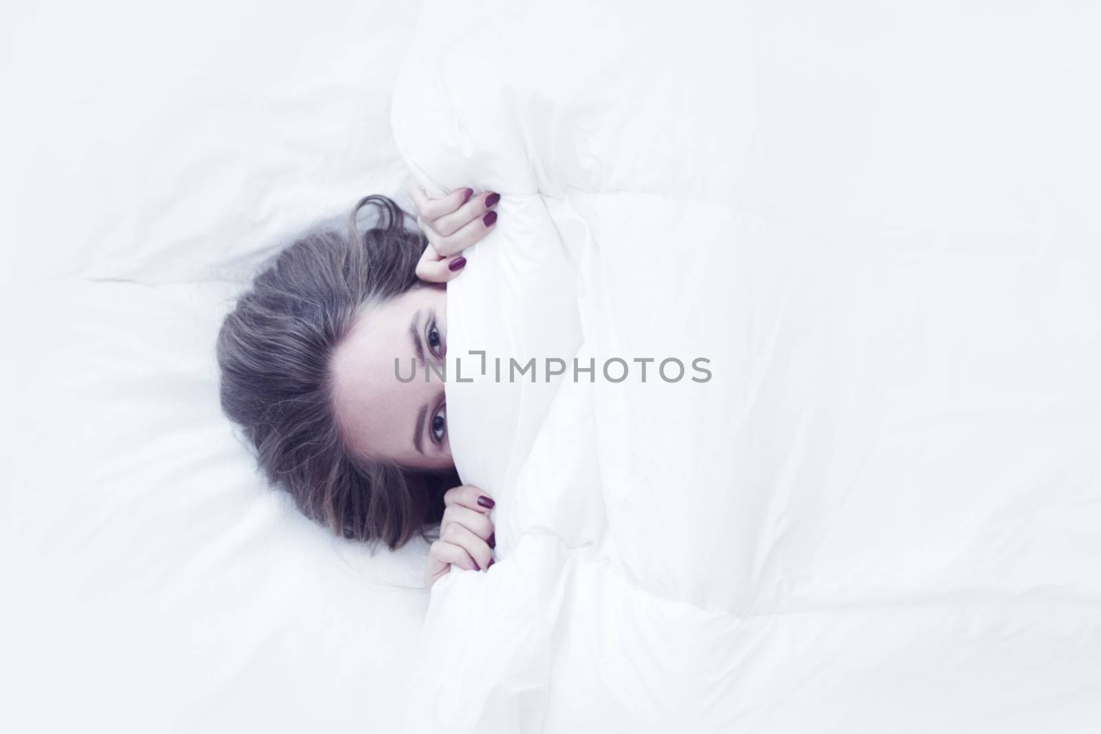 Young girl wake up in bed, top view