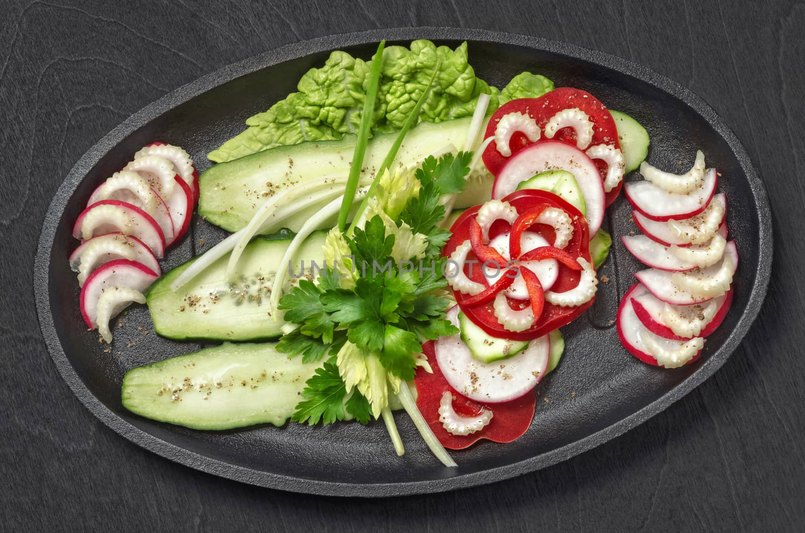 Chopped vegetables, on a black wooden background by Gaina