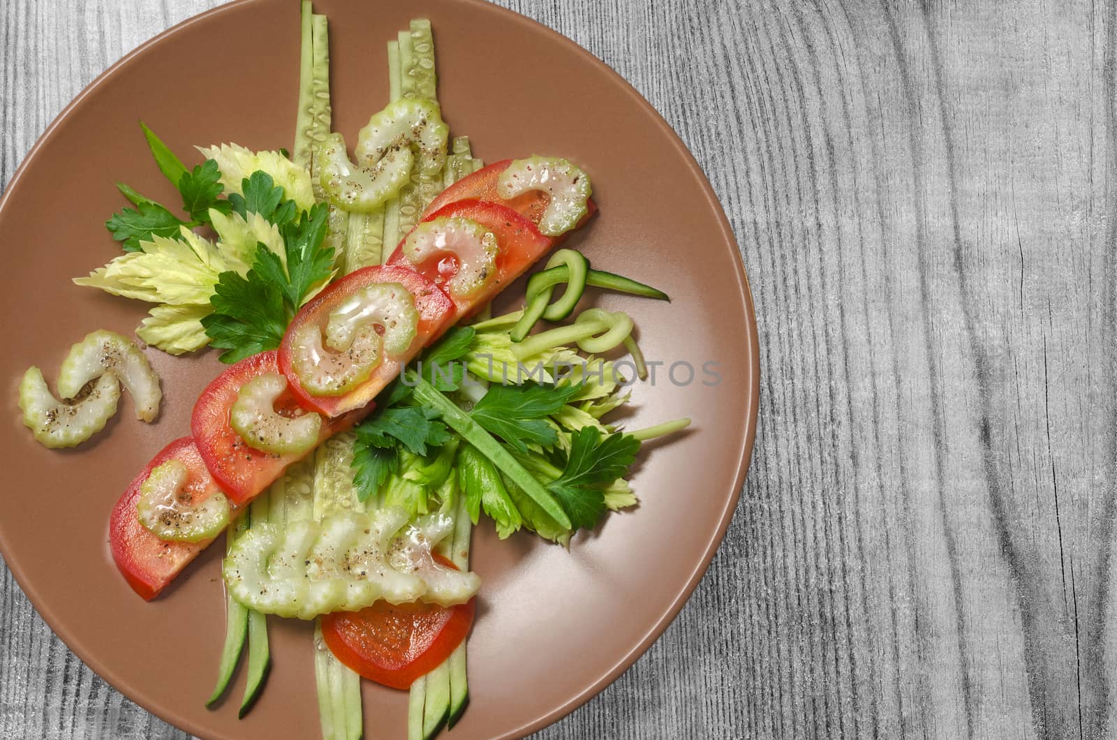 A dish of sliced vegetables, on a gray wooden background.