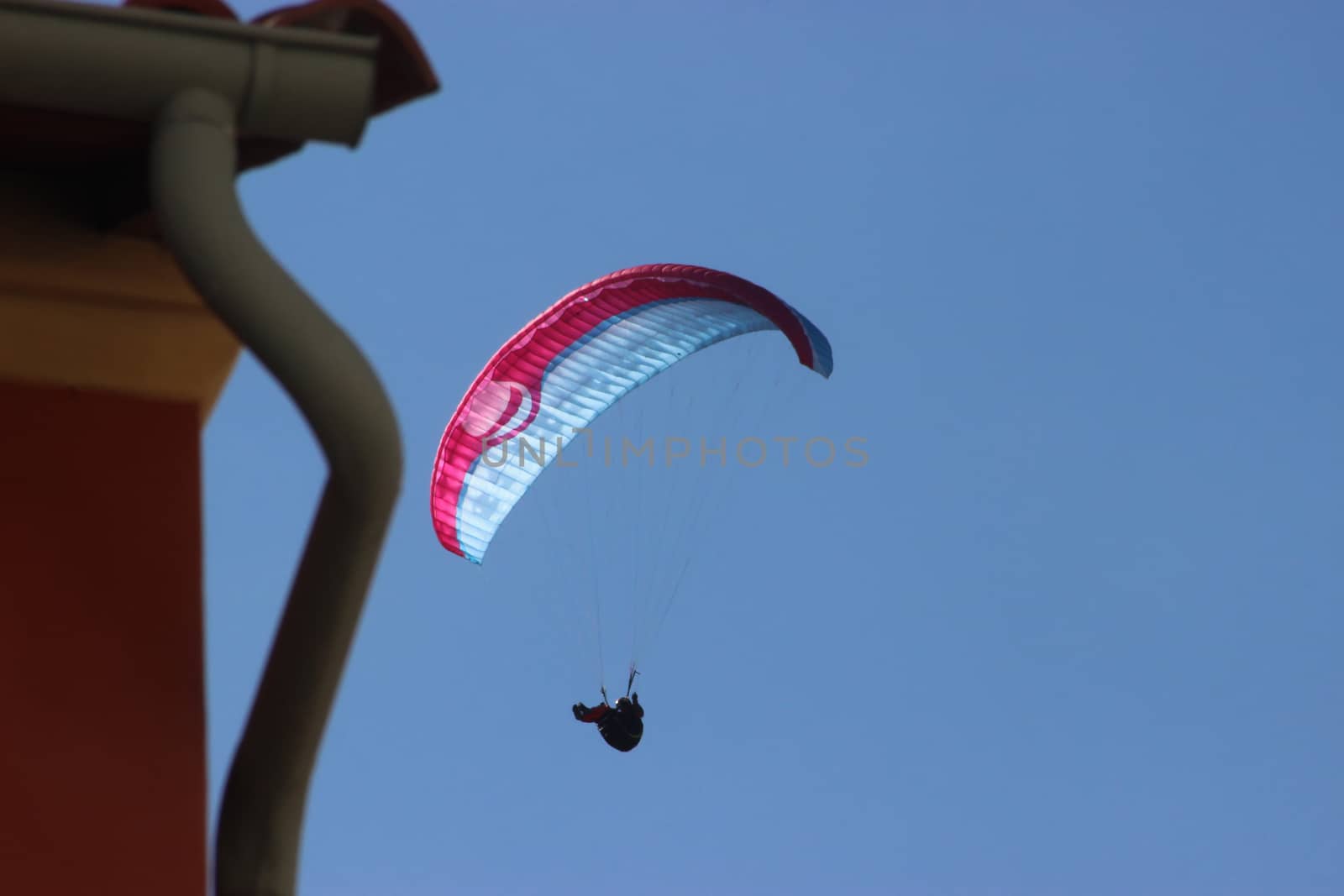 Paraglider Flying On Clear Blue Sky Background