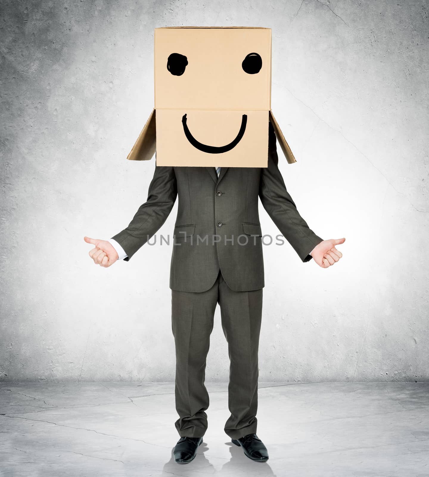 Businessman gesturing with box on head and smiley face
