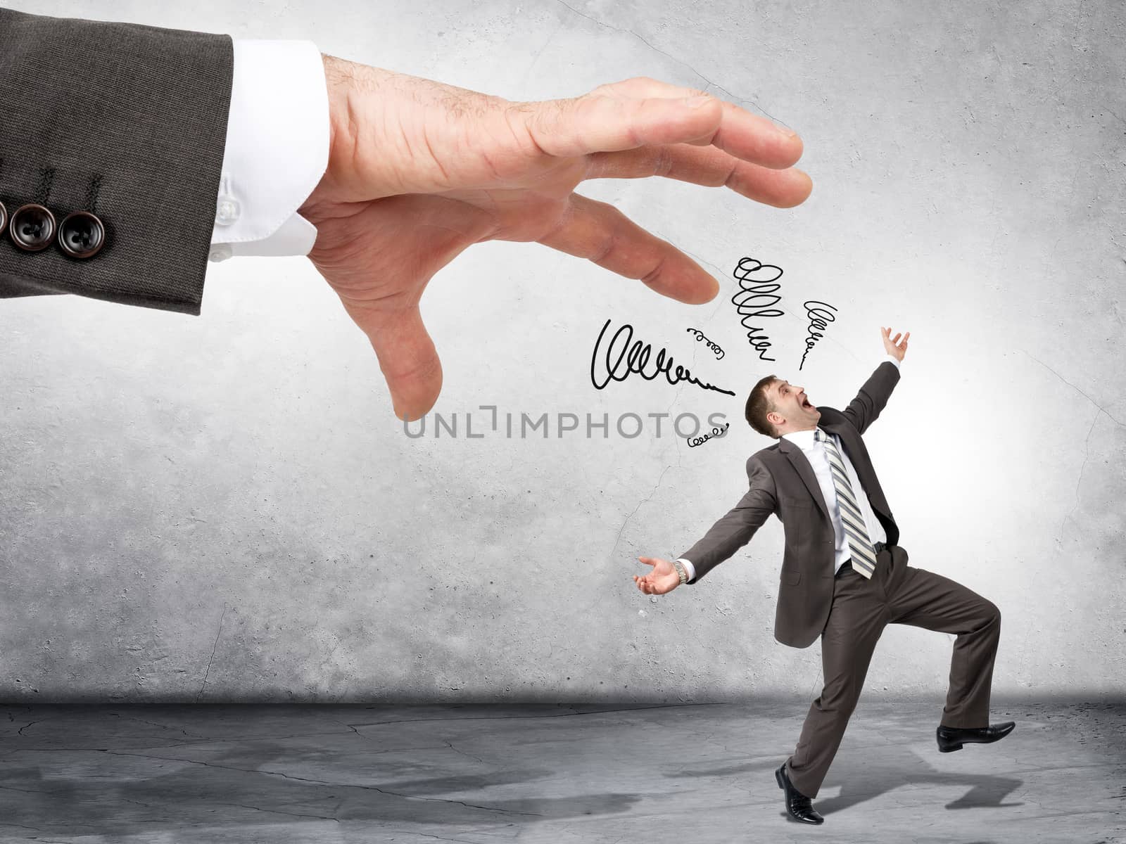 Business boss hand catching scared employee on grey wall background