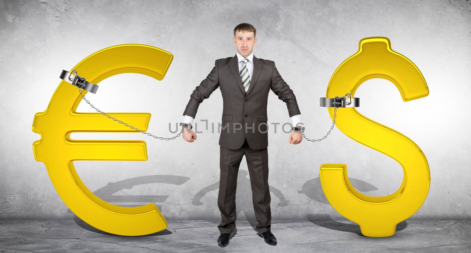 Man chained with golden dollar and euro signs on grey bckground