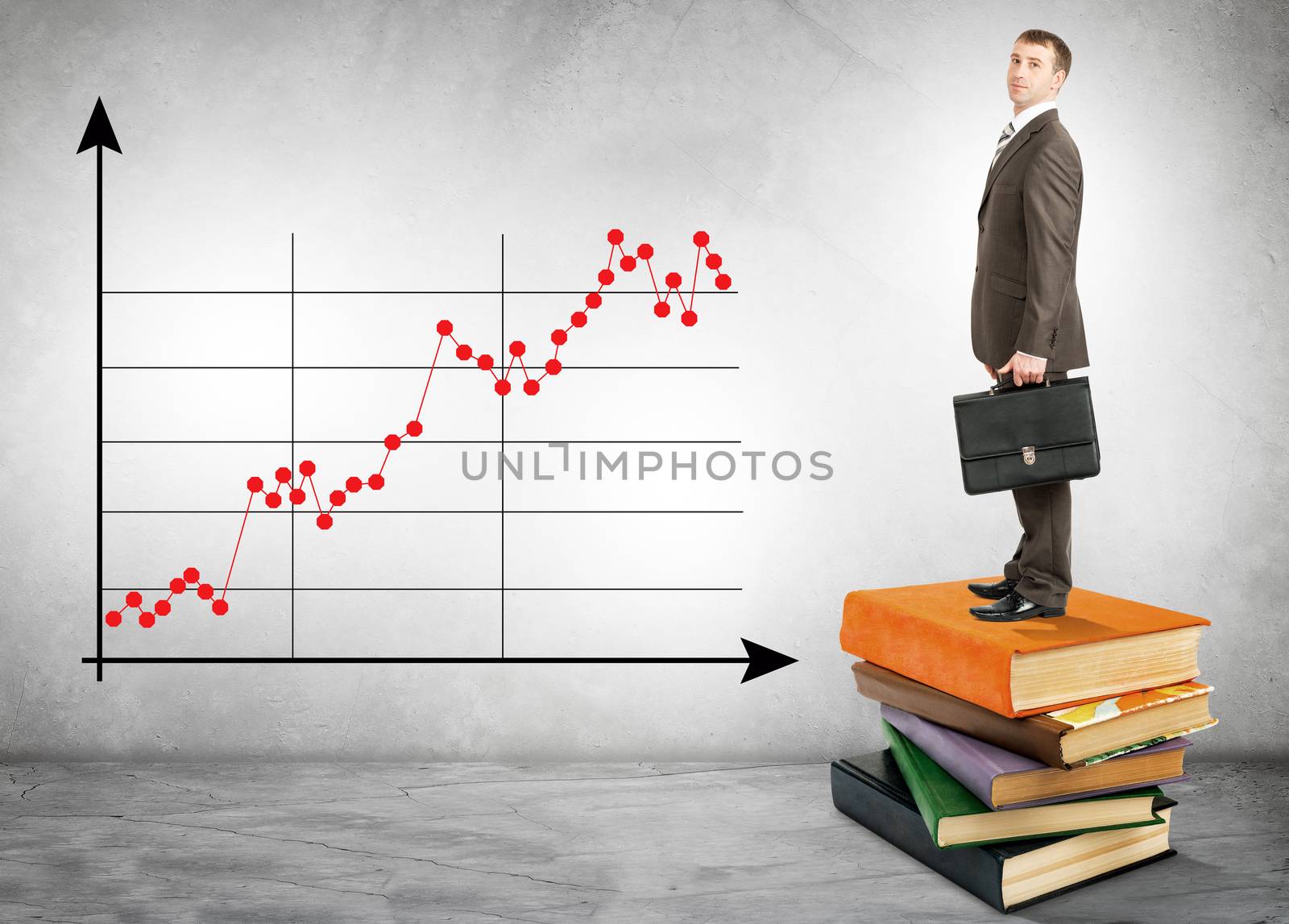 Businessman standing on books with chart on wall