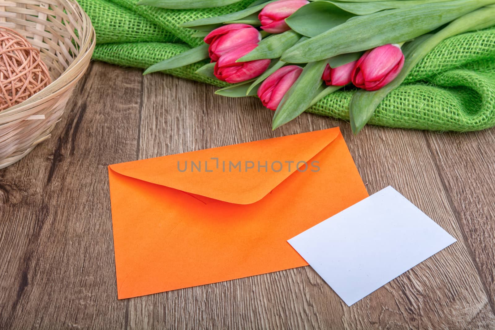 Envelope with sheet of paper and red tulips on a wooden background