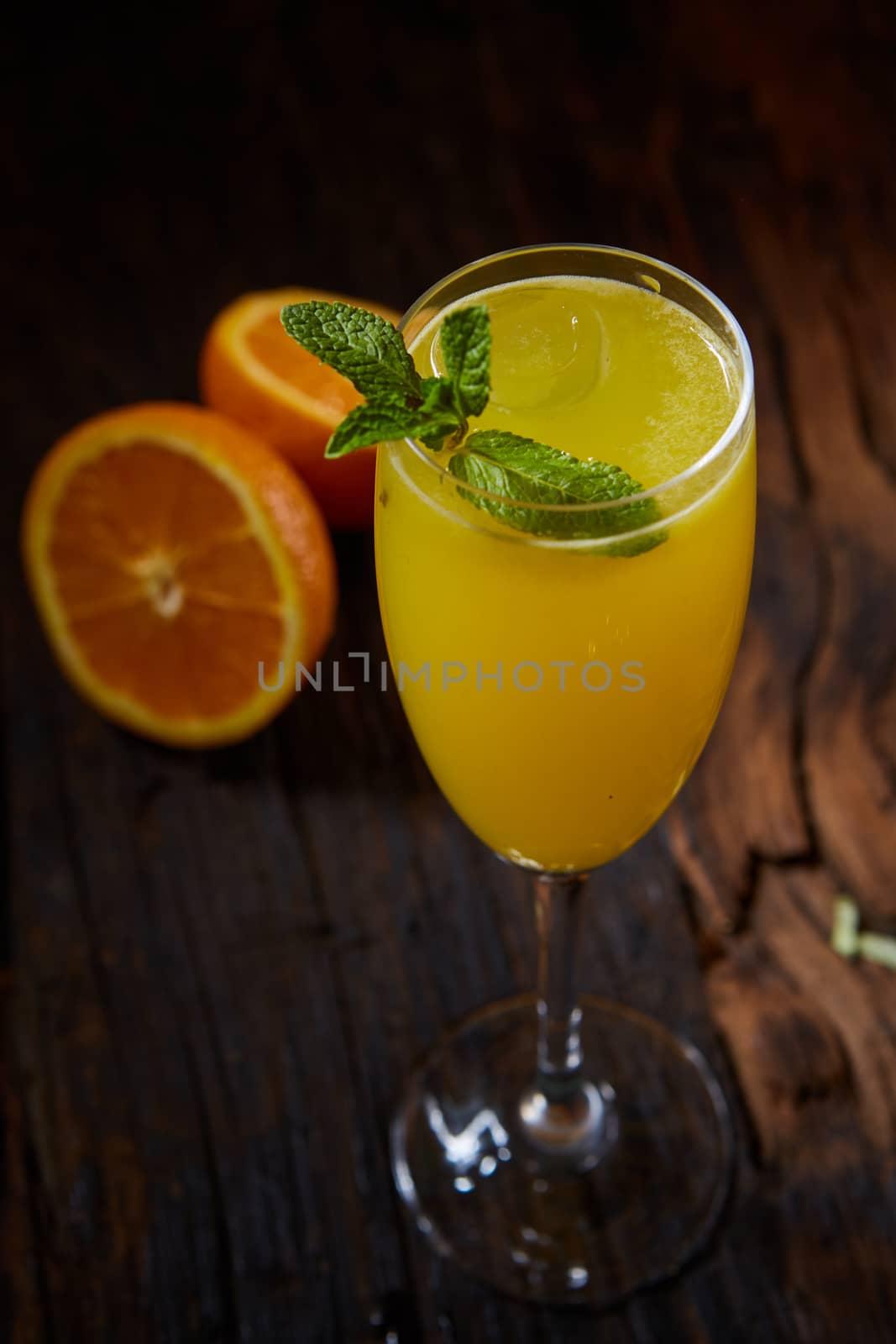 Orange cocktail decorated mint leaves and oranges on rustic wooden table