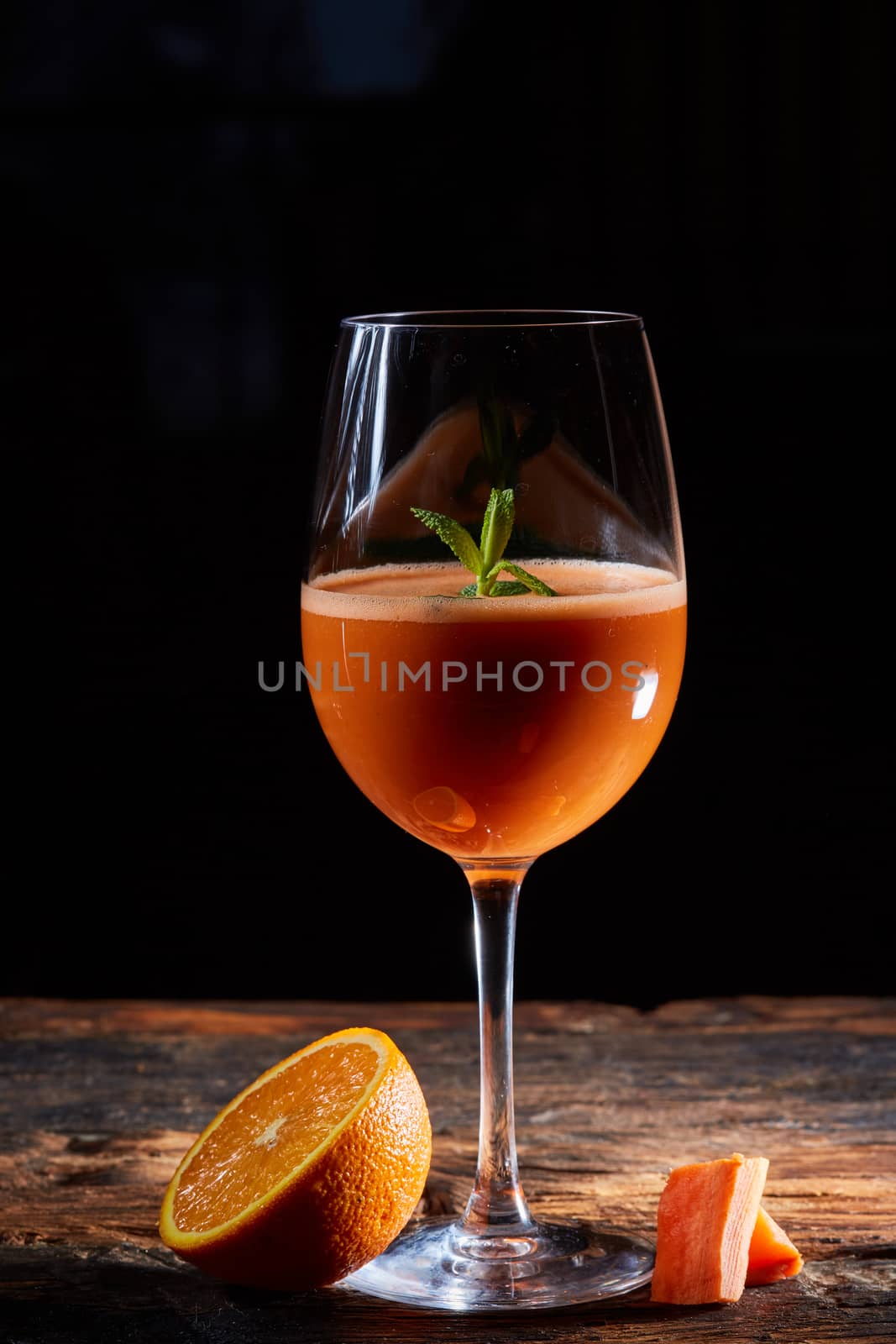 Orange carrot smoothie in glass decorated mint on wood