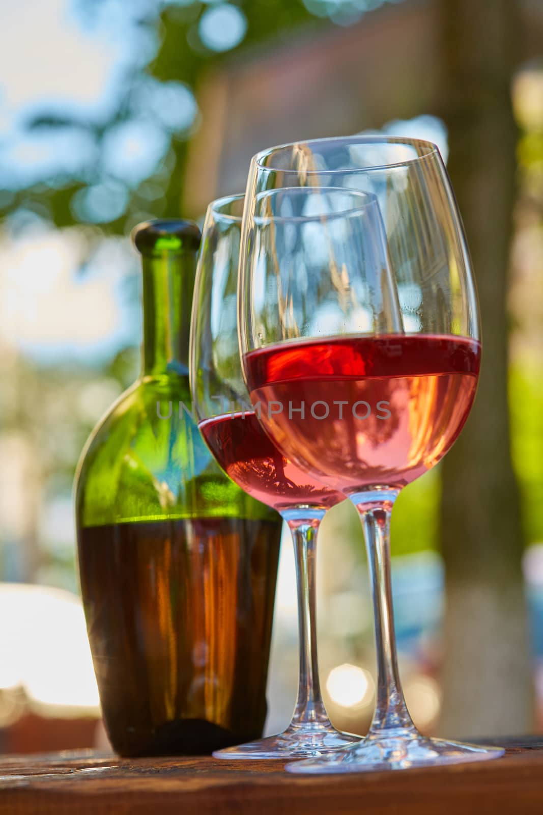 two wine glasses filled with red wine and wine bottle in background. Soft focus