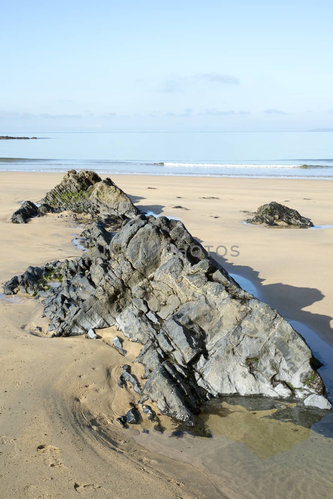 beautiful soft waves break on the black rocks by morrbyte