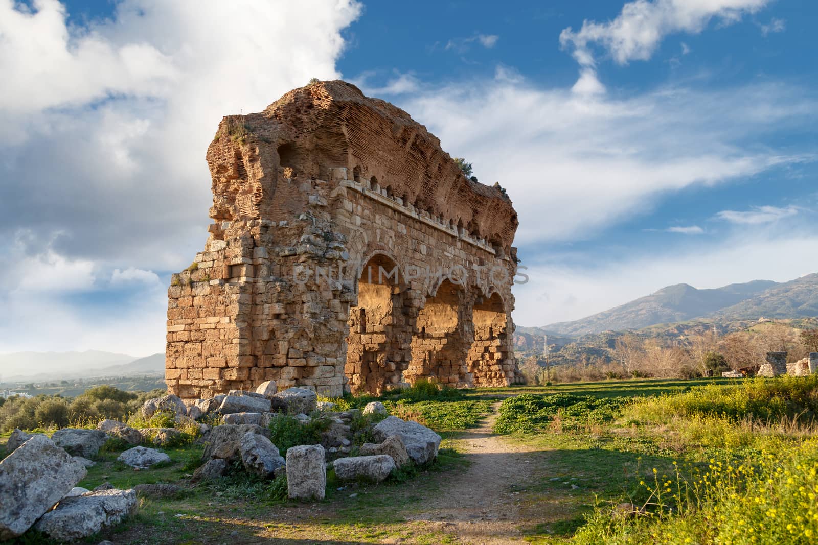 View of Tralleis Ancient City in Aydın, Turkey, stone ruins from 2nd century on cloudy blue sky background.