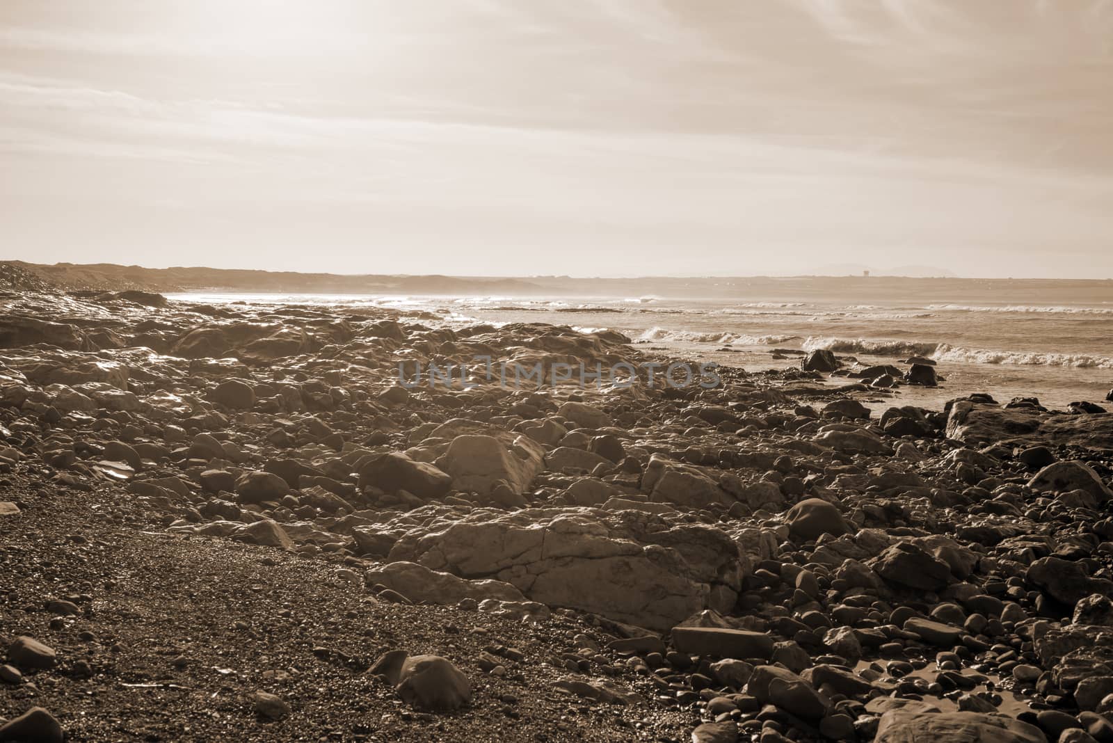 waves break on the black rocks at ballybunion beach in ireland in sepia