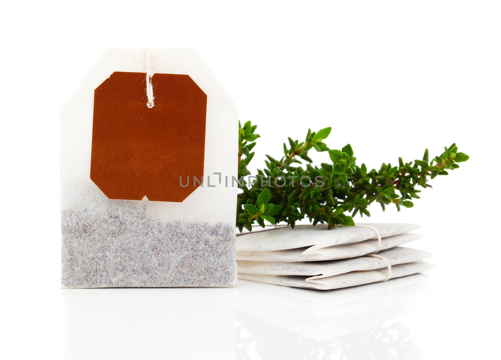 Teabag with green thyme herbs. Isolated on white background
