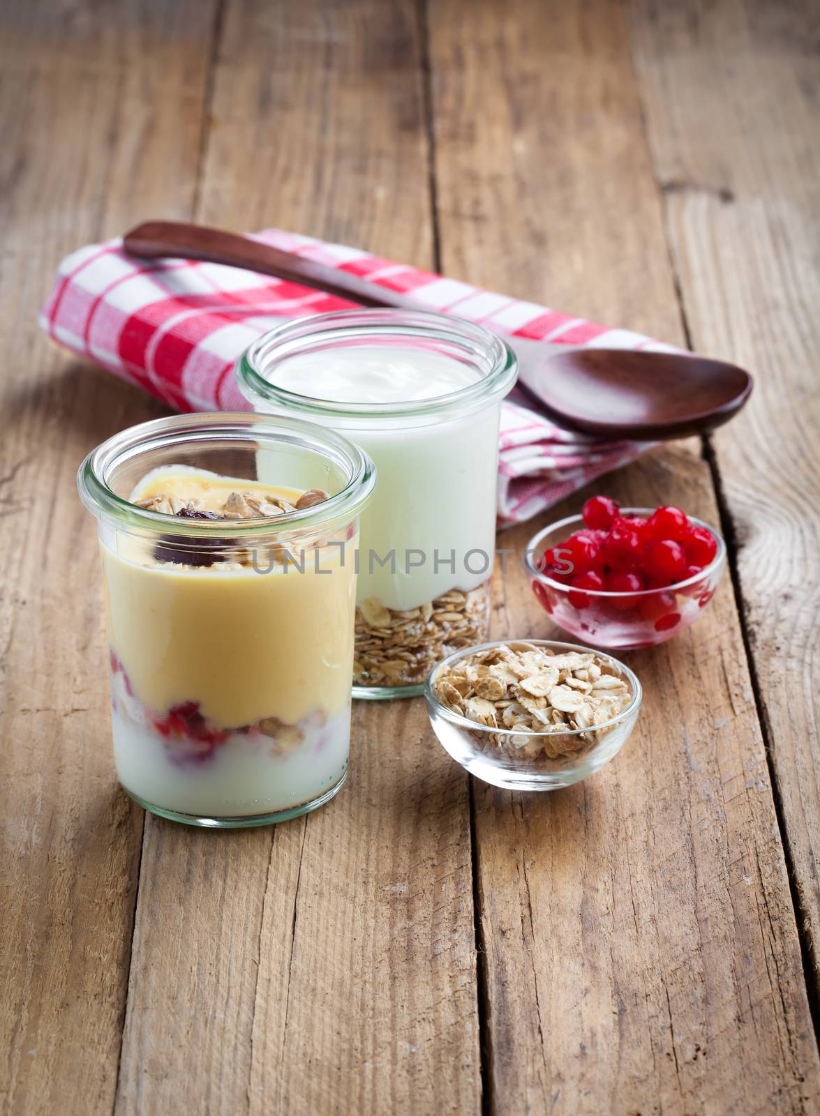 Healthy yougurt with berry in a glass jars on wooden background by motorolka