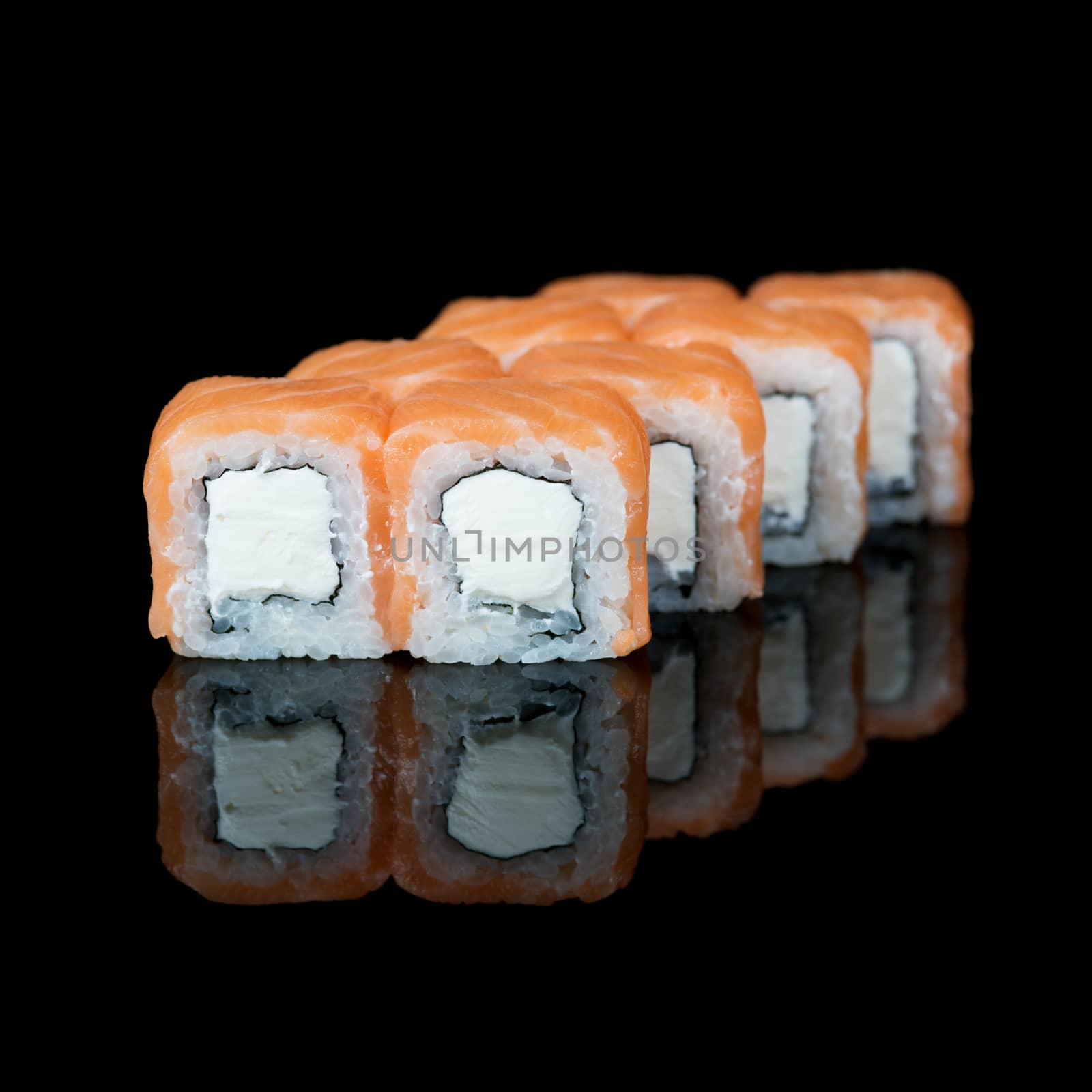 Sushi rolls with salmon and soft cheese on  black background