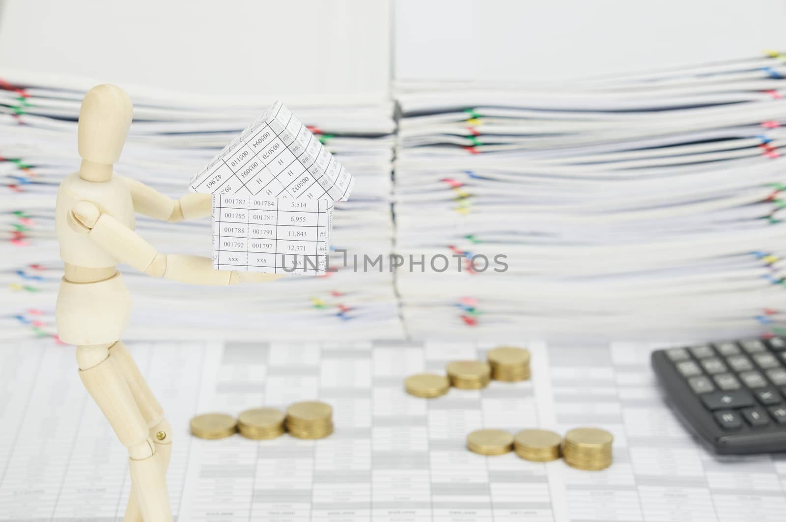 Wooden dummy holding house have blur calculator and gold coins by eaglesky