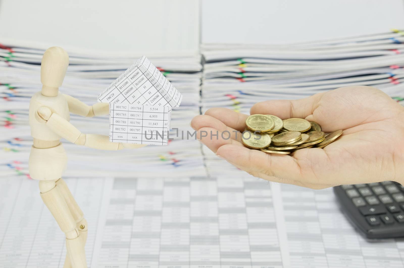 Man holding gold coins to buy house from wooden dummy by eaglesky