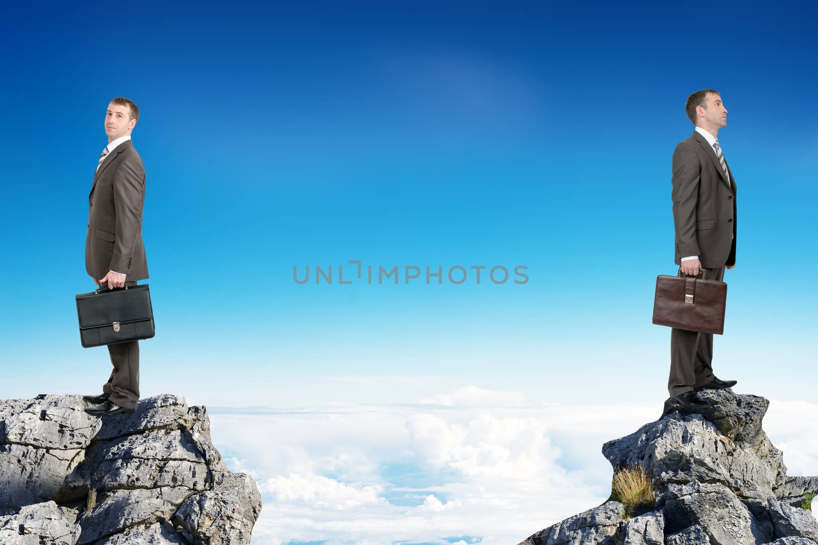Young businessmen with suitcases standing on peaks with their backs to each other