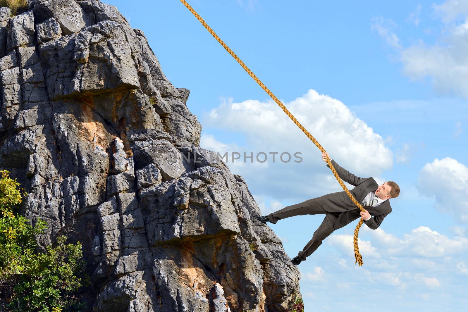 Business man climbs mountain within help of rope