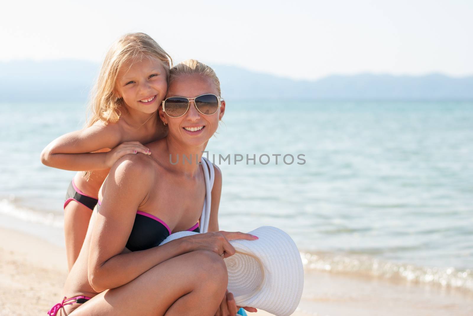 Mother and daughter posing at the beach. Looking at camera