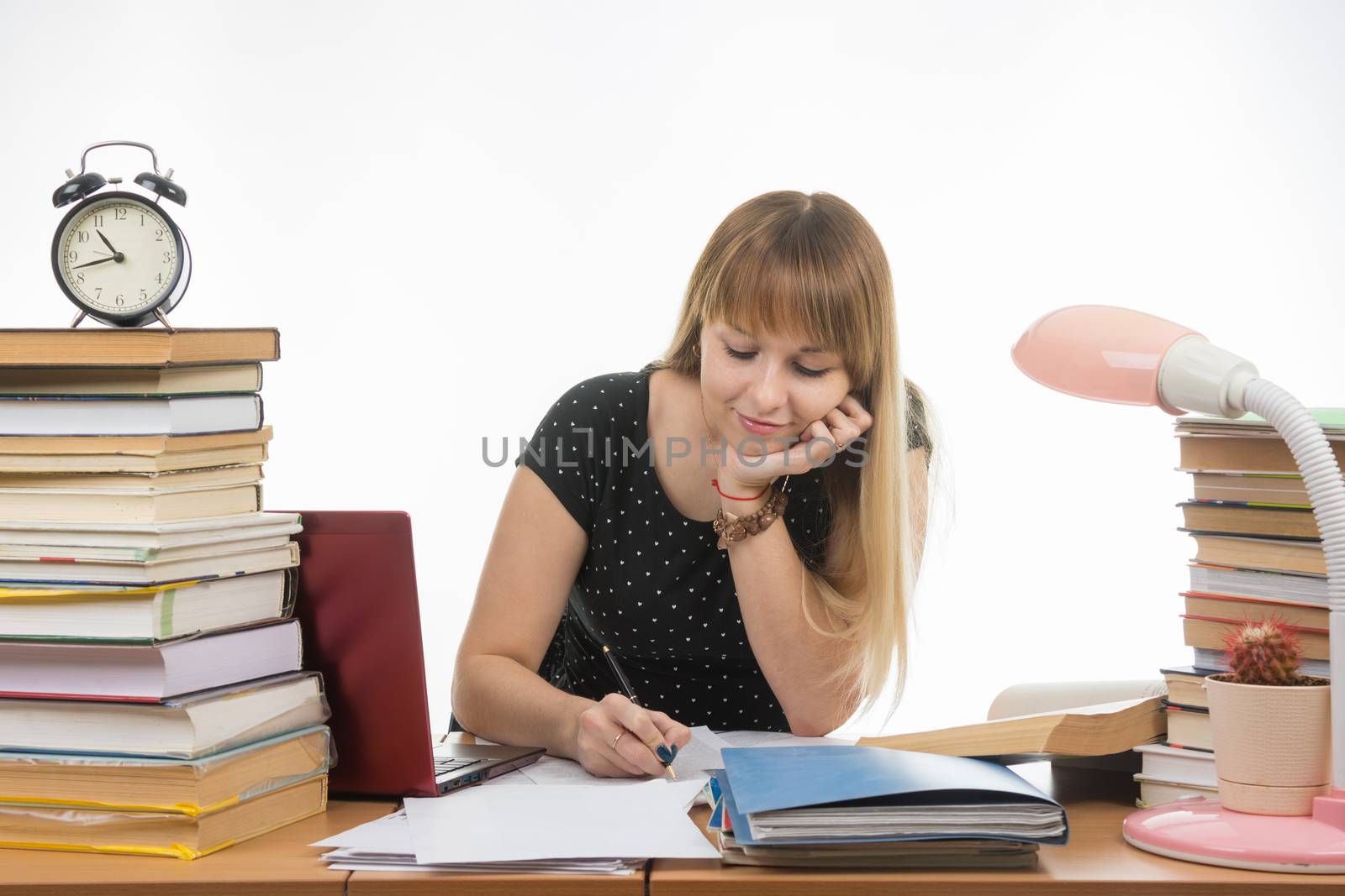 college student smiling engaged at the table cluttered with books in the library