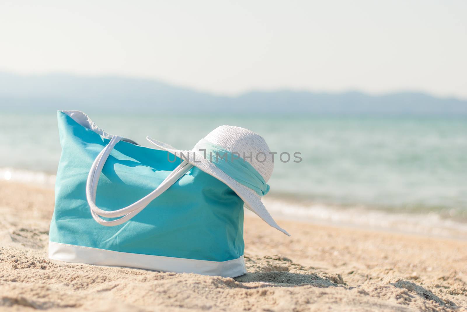 Turquoise bag and white hat on the beach.
