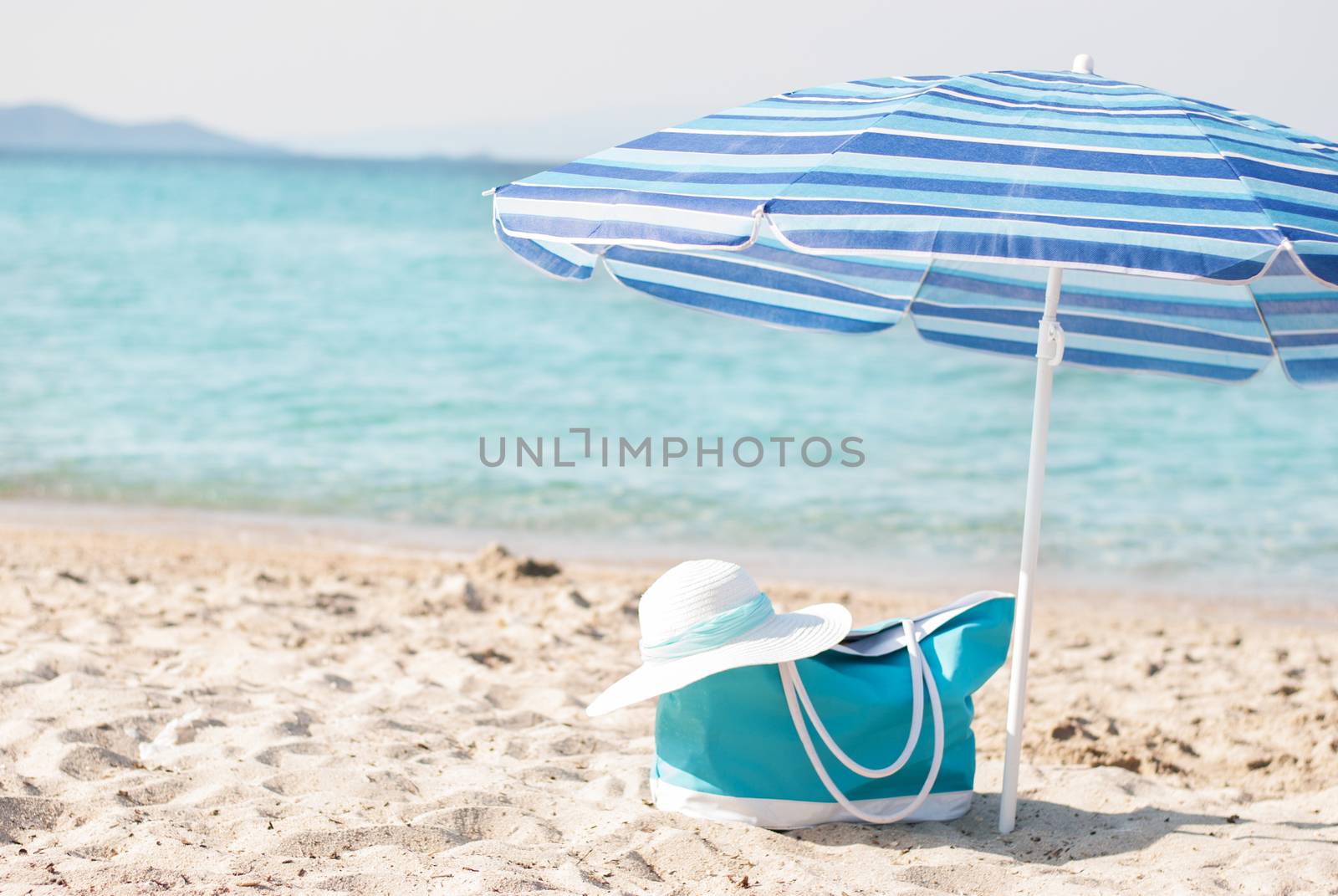 Turquoise bag and white hat on the beach.