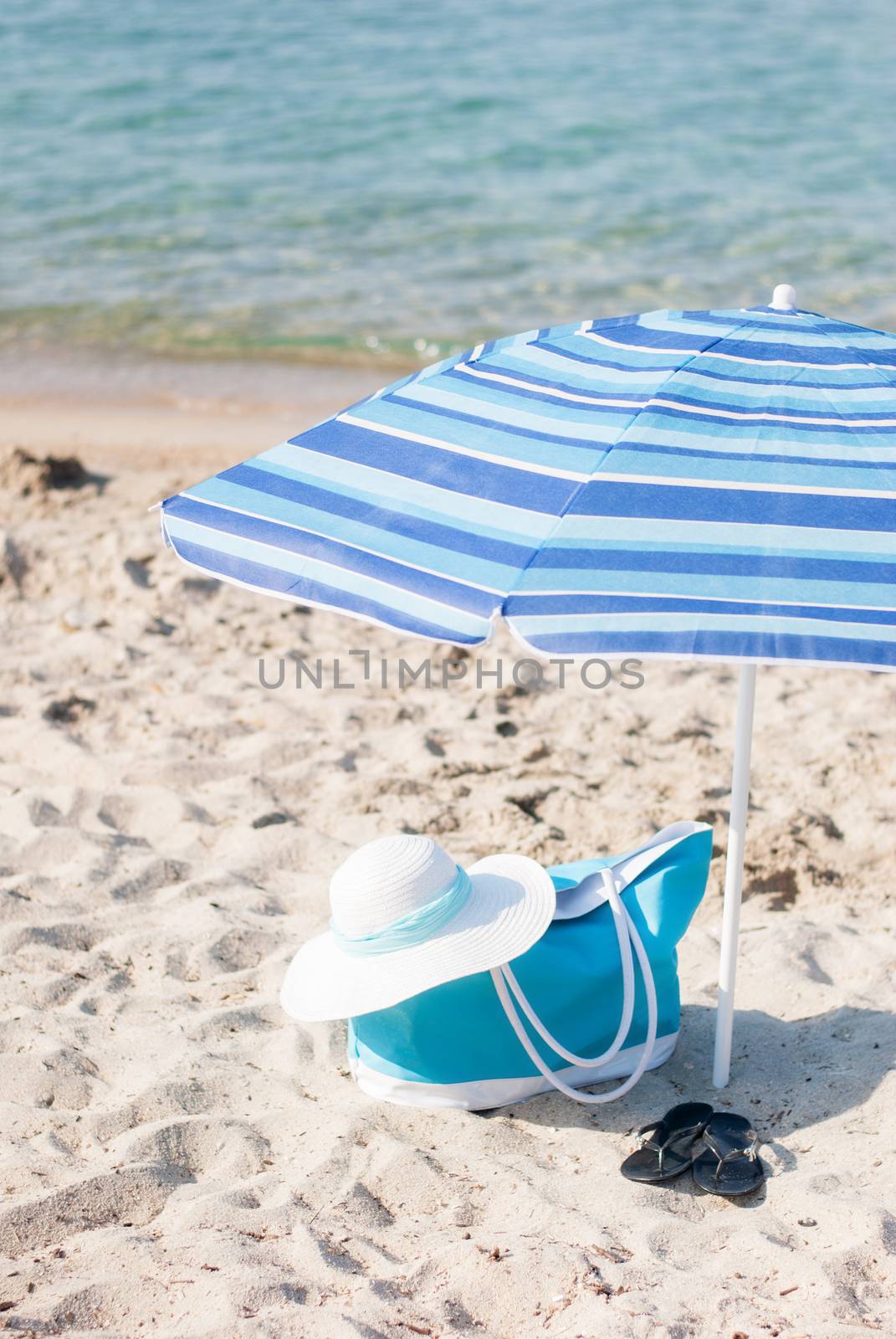 Turquoise bag and white hat on the beach.