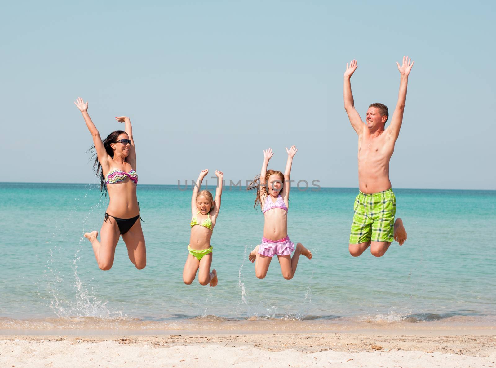 Family of four jumping at beach