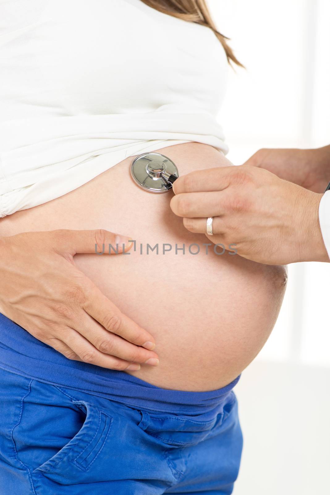 Pregnant woman examining by a doctor with a stethoscope