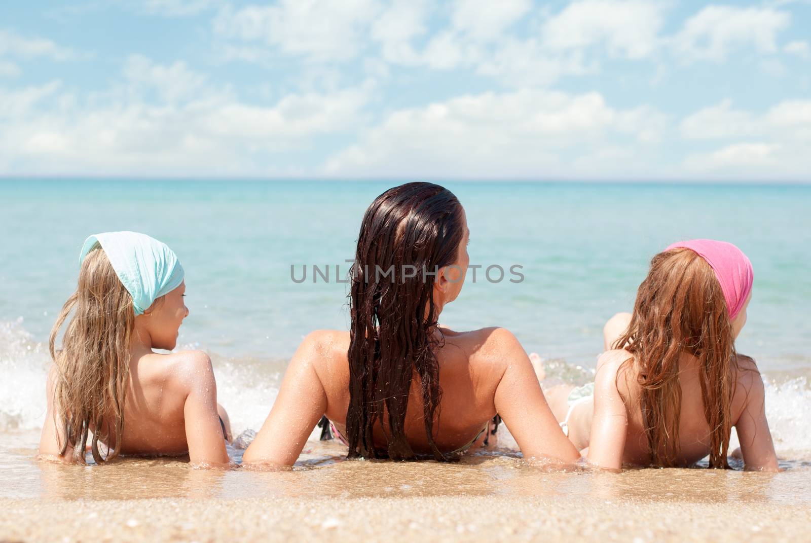Family of three relaxing at beach. Rear View.