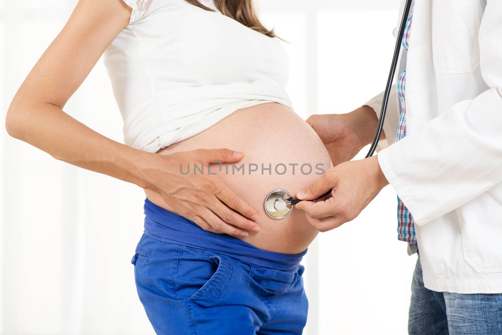 Pregnant woman examining by a doctor with a stethoscope