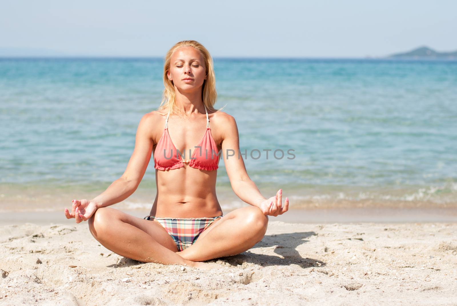 Young woman meditating on the beach.