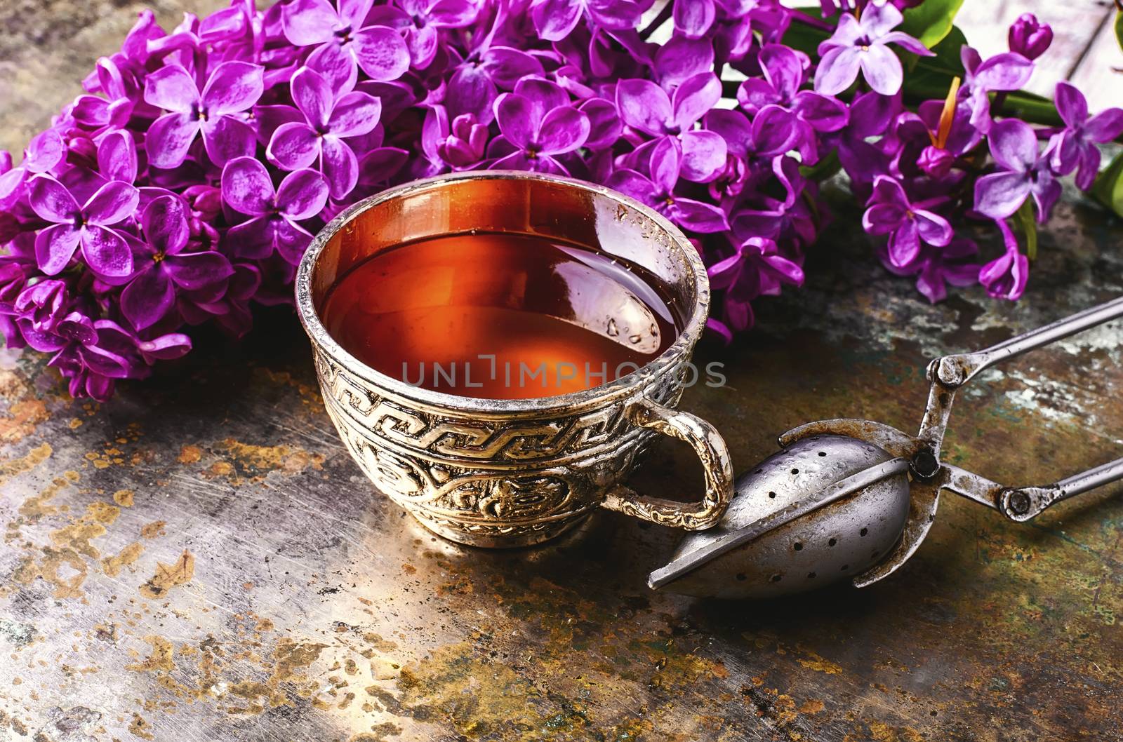 Brew tea in a stylish circle,branch of lilac on metallic background