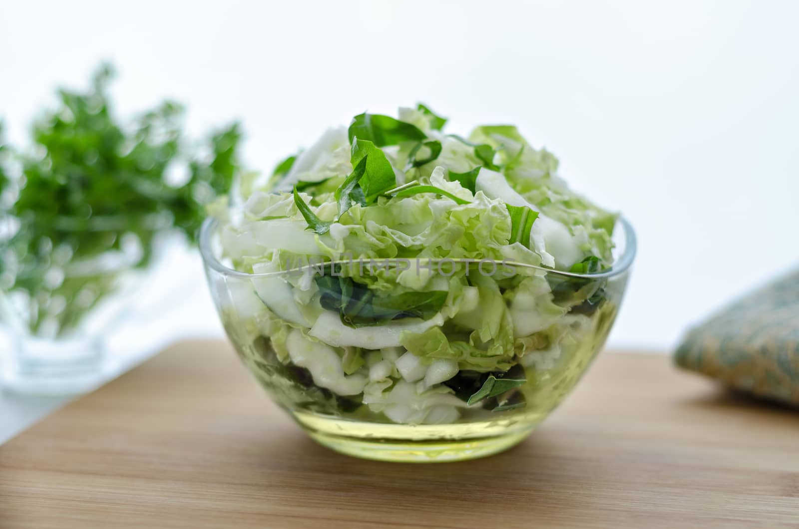 Salad from Chinese cabbage and dandelion leaves, on the table. Morning light, bokeh, and a napkin.