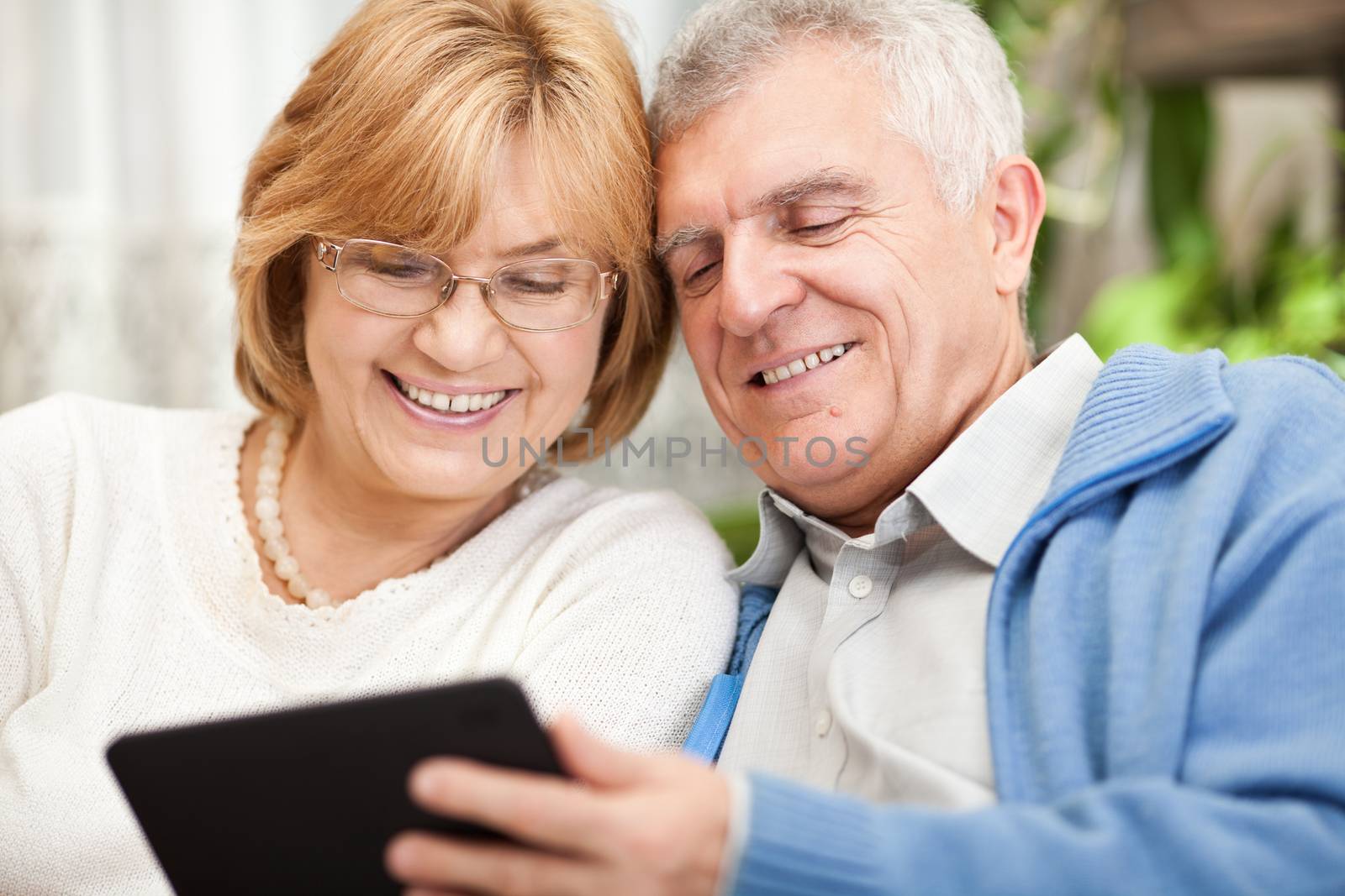 Happy senior couple using tablet PC at home