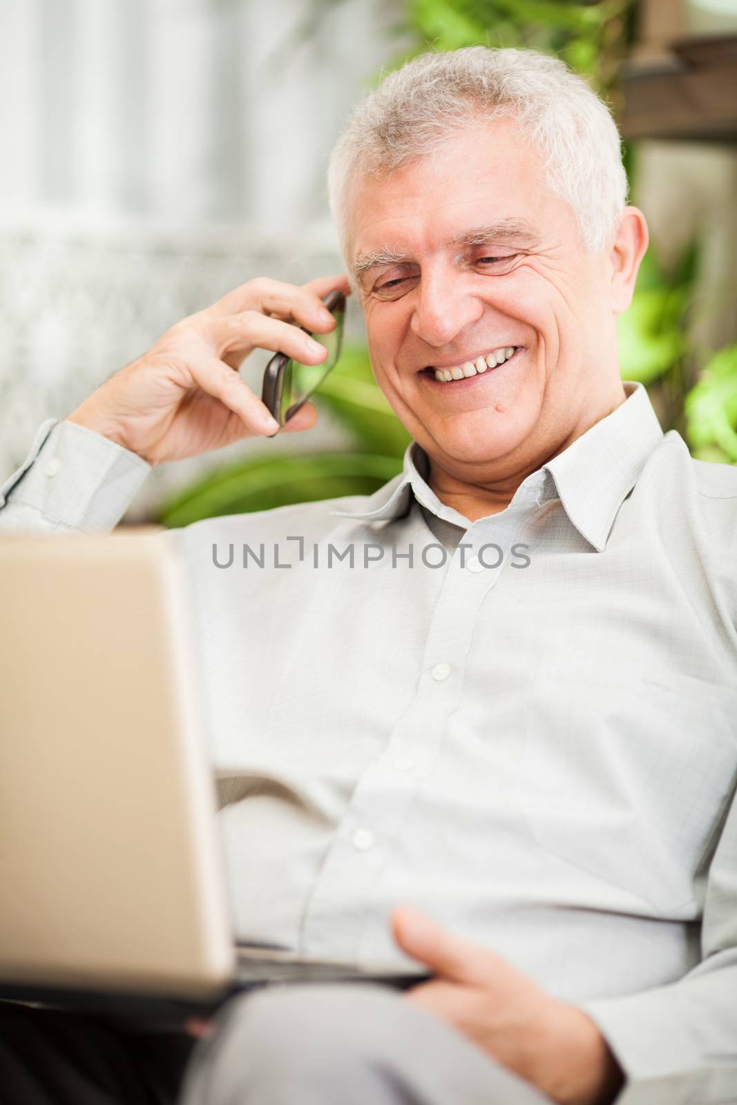 Happy senior businessman working at home on laptop