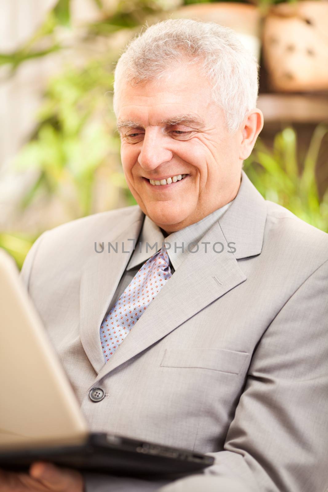Happy senior businessman working at home on laptop