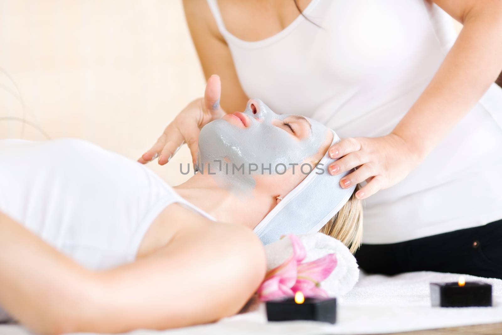 Young beautiful woman receiving cosmetic facial mask in spa beauty salon