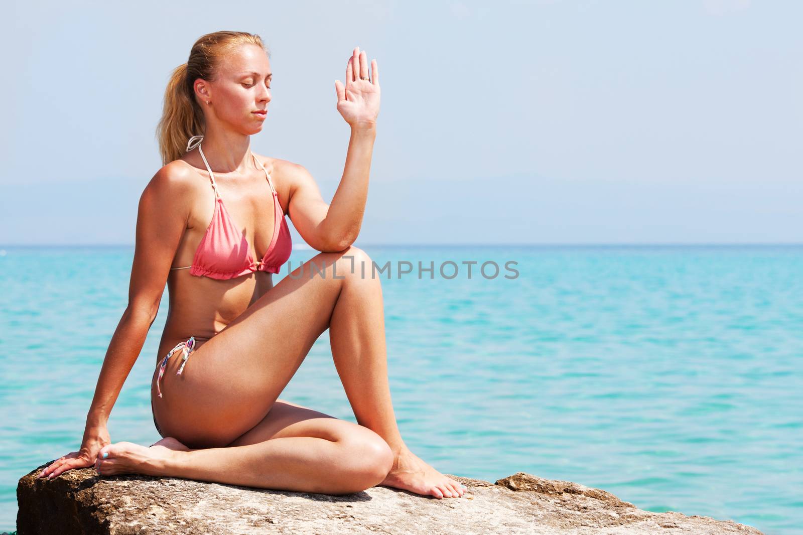 Young Woman doing yoga on rocks by the sea