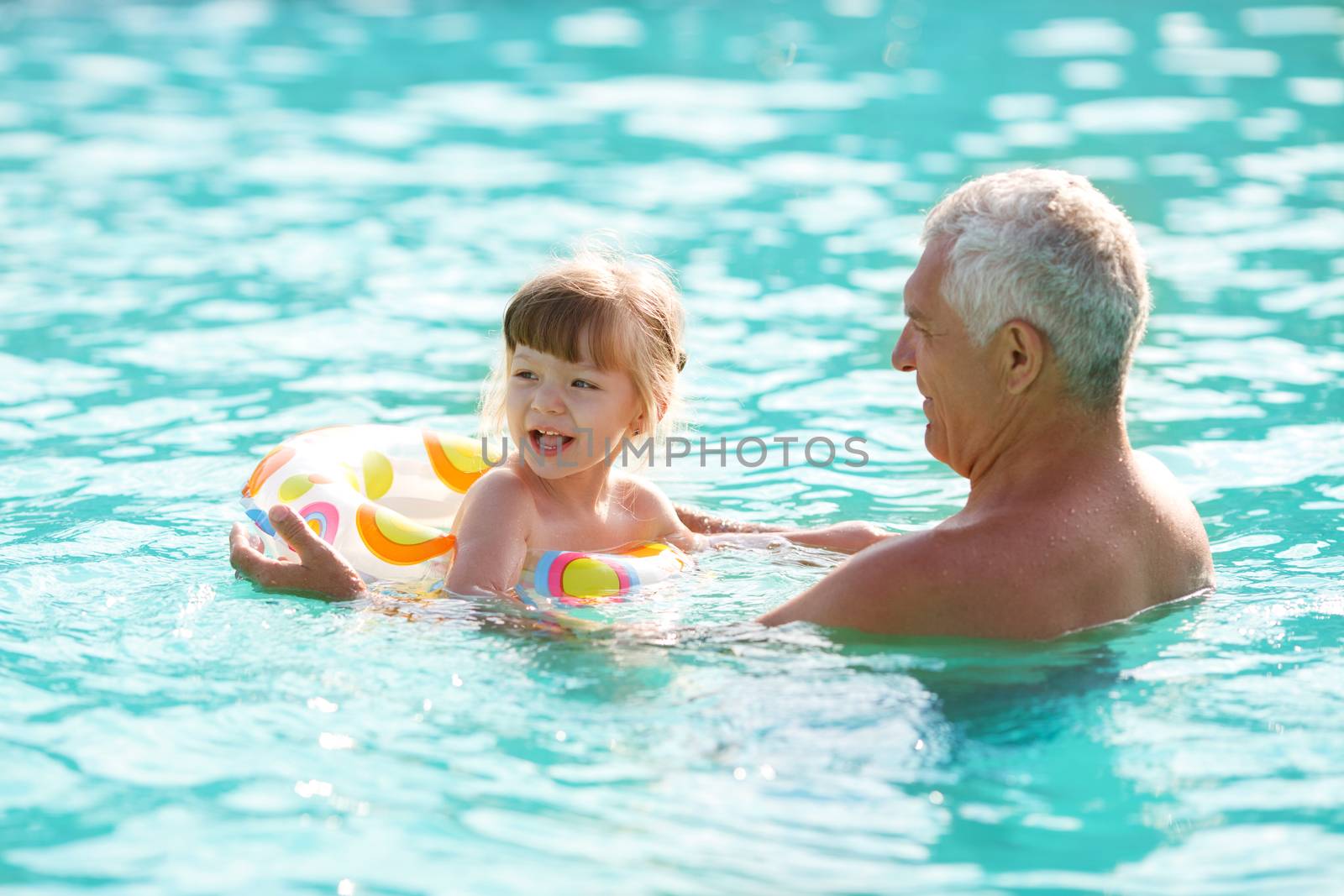 grandfather and granddaughter swimming in the pool