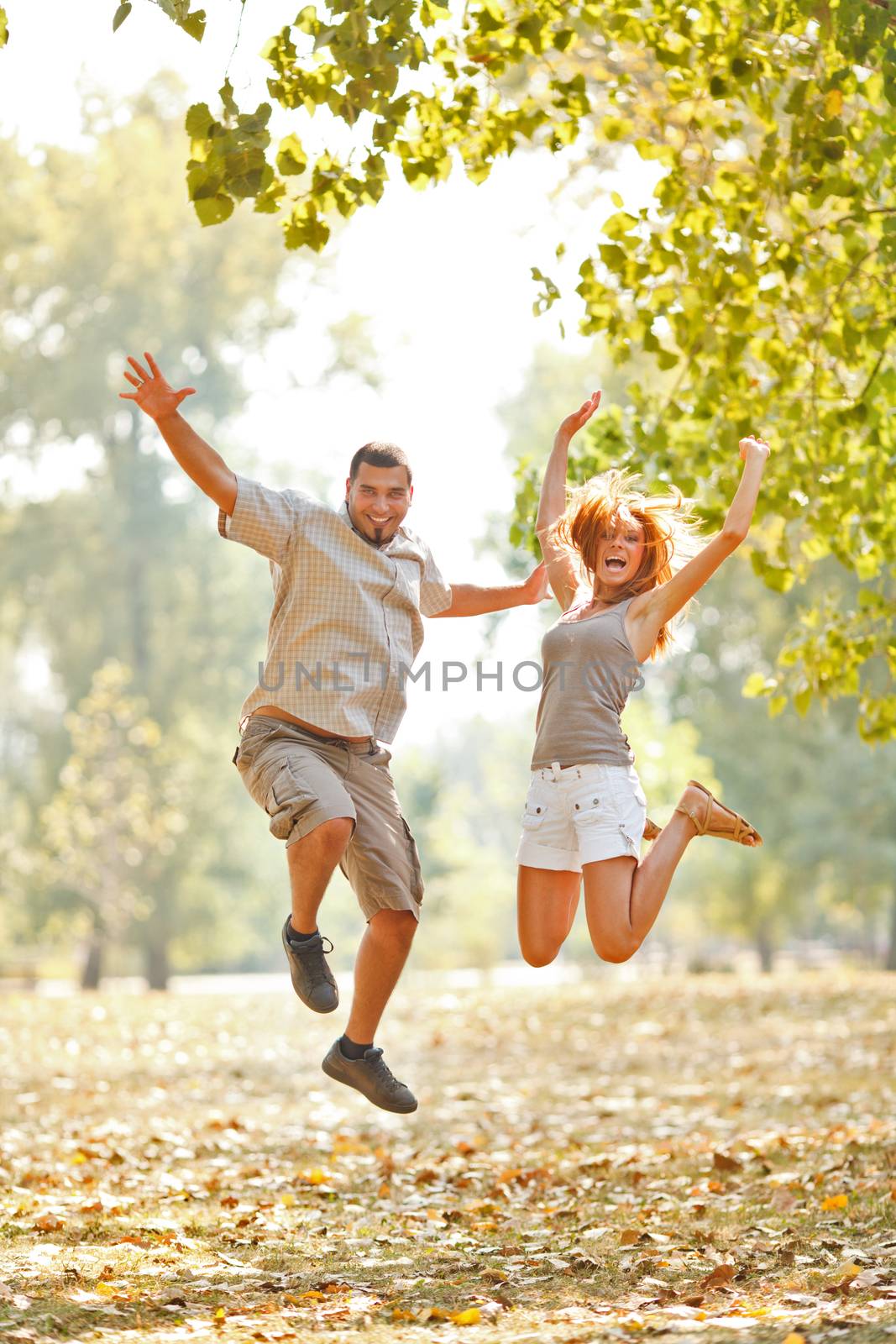 Beautiful happy couple jamping in the park 