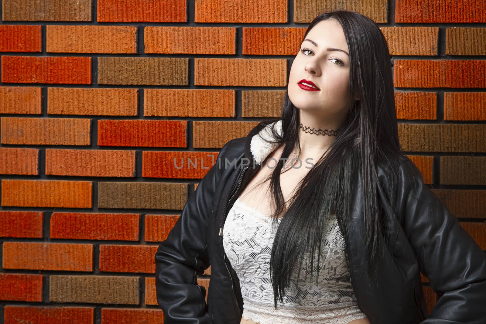 twenty something girl standing against a brick wall