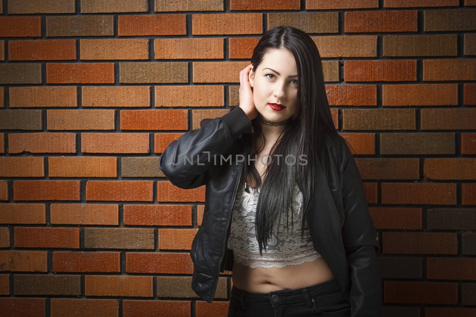 Young woman against a brick wall with rocker look