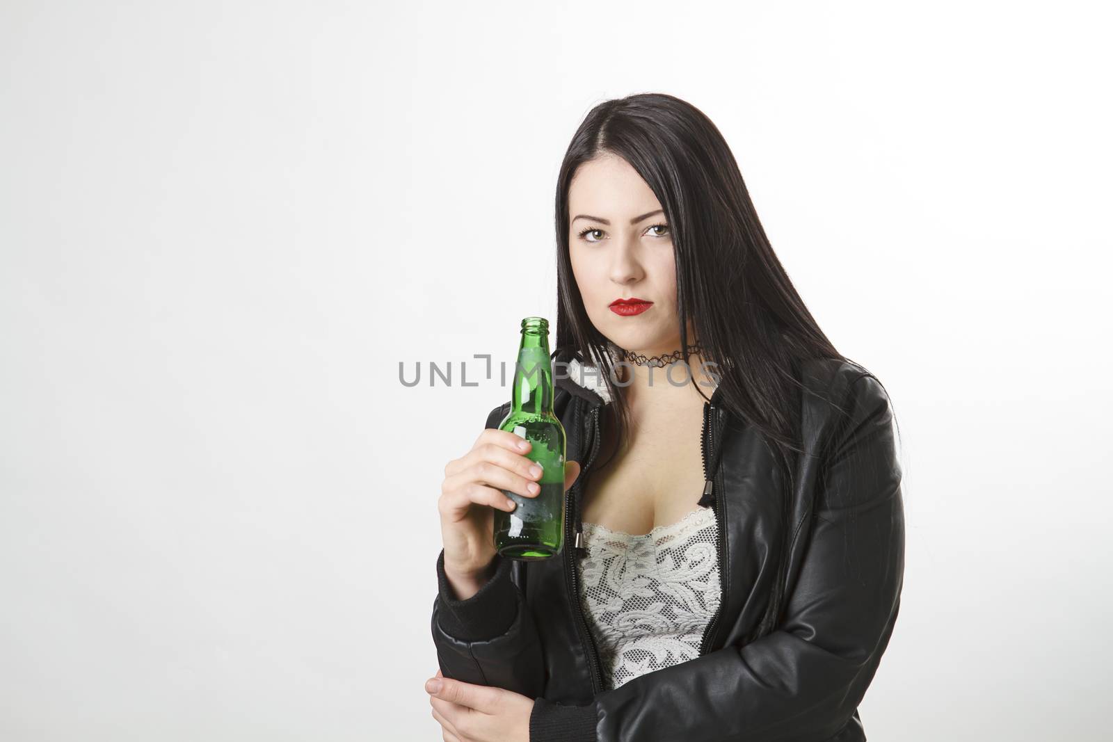 trendy twenty something woman wearing a lace top and a coat, holding a green bottle of beer