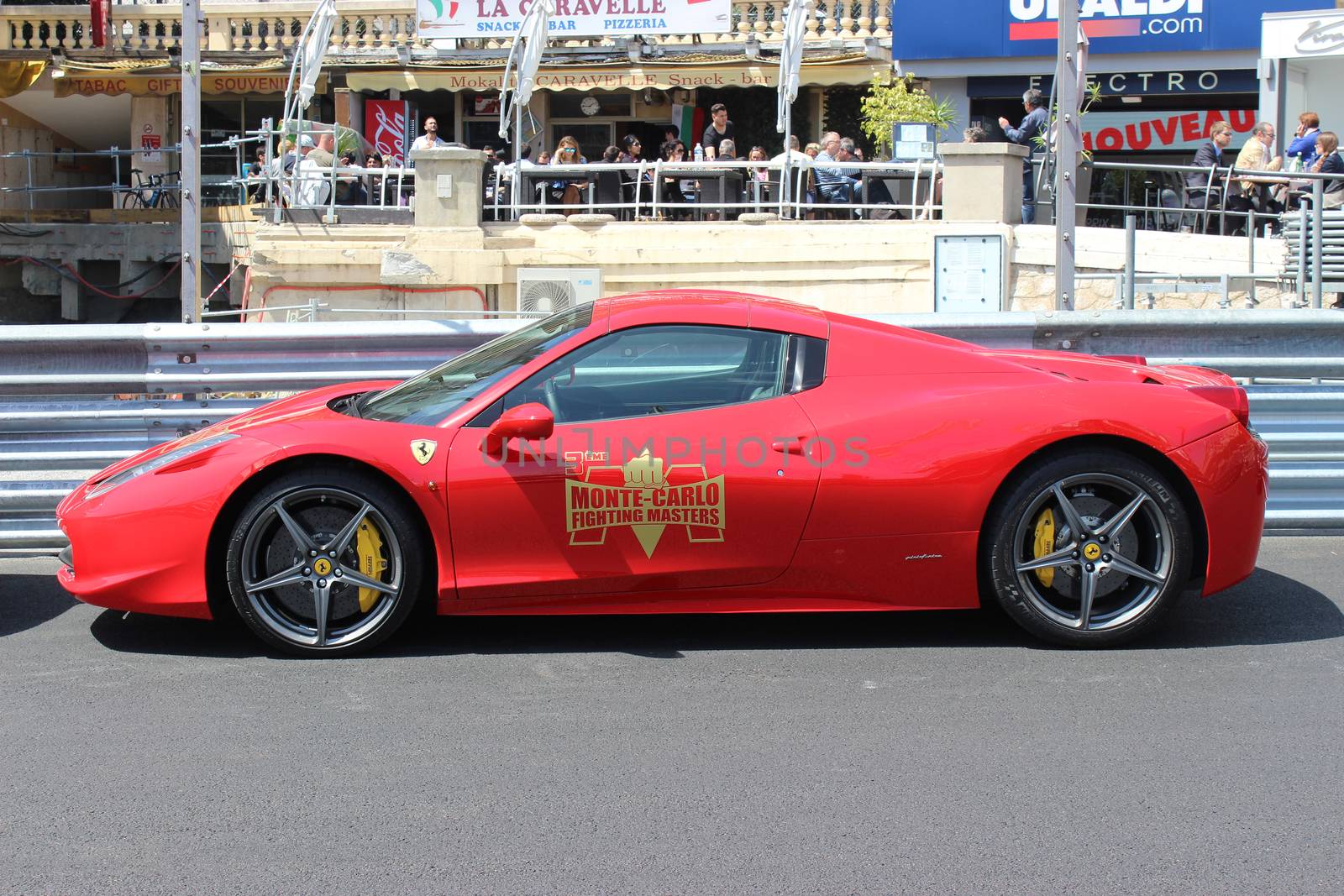 Monte-Carlo, Monaco - April 28, 2016: Red Ferrari 458 Italia Parked on the Street in Monaco. Guardrail of the Monaco Grand Prix in the Background