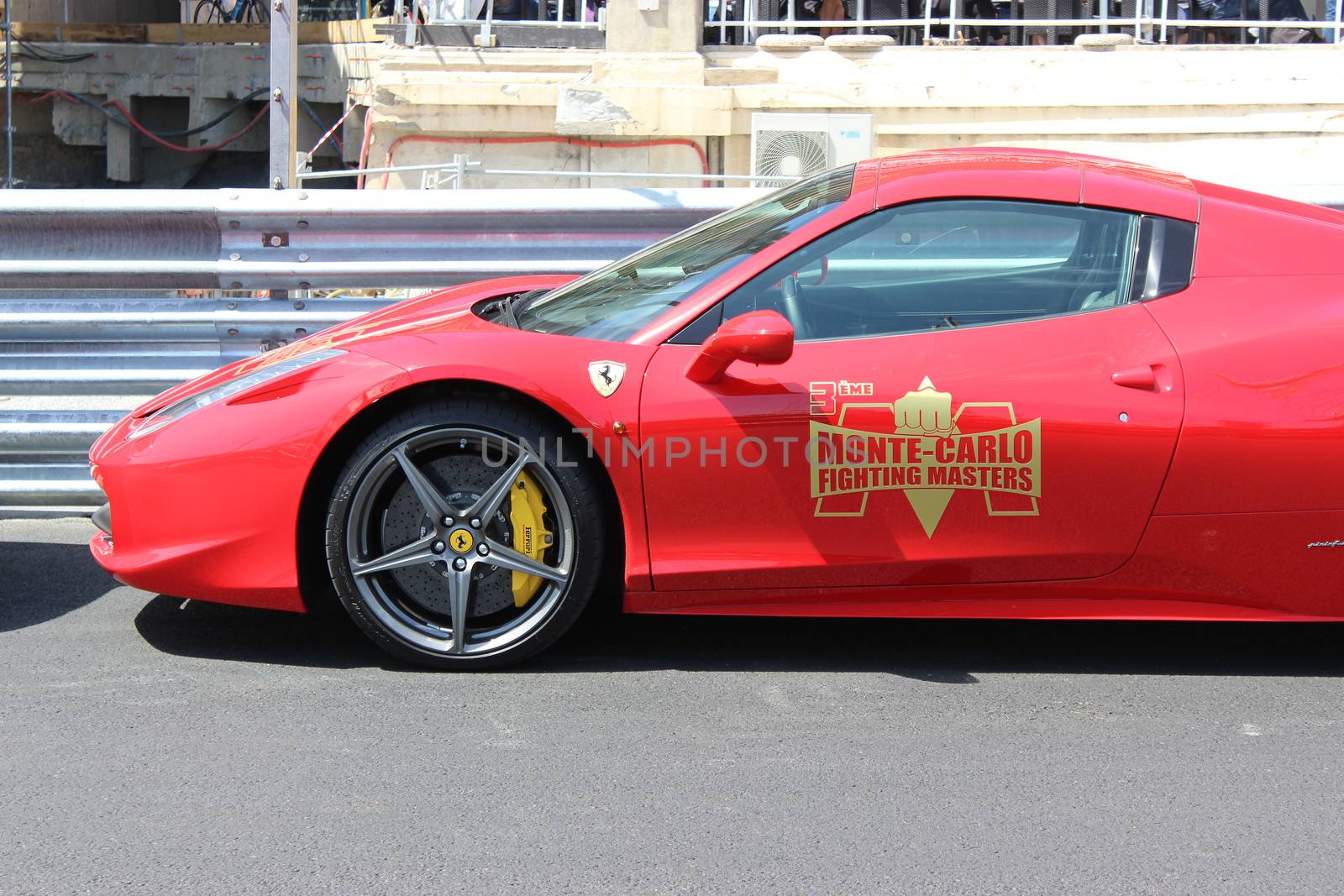 Monte-Carlo, Monaco - April 28, 2016: Red Ferrari 458 Italia Parked on the Street in Monaco. Guardrail of the Monaco Grand Prix in the Background