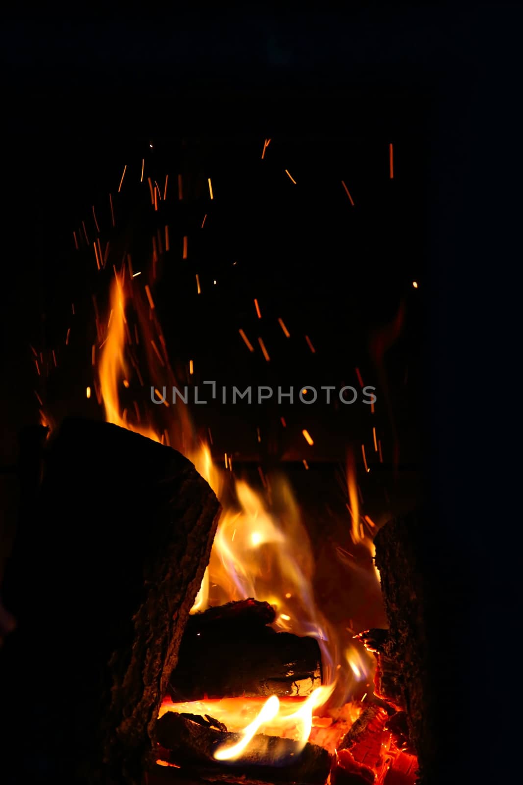 Crest of flame on burning wood in fireplace close up
