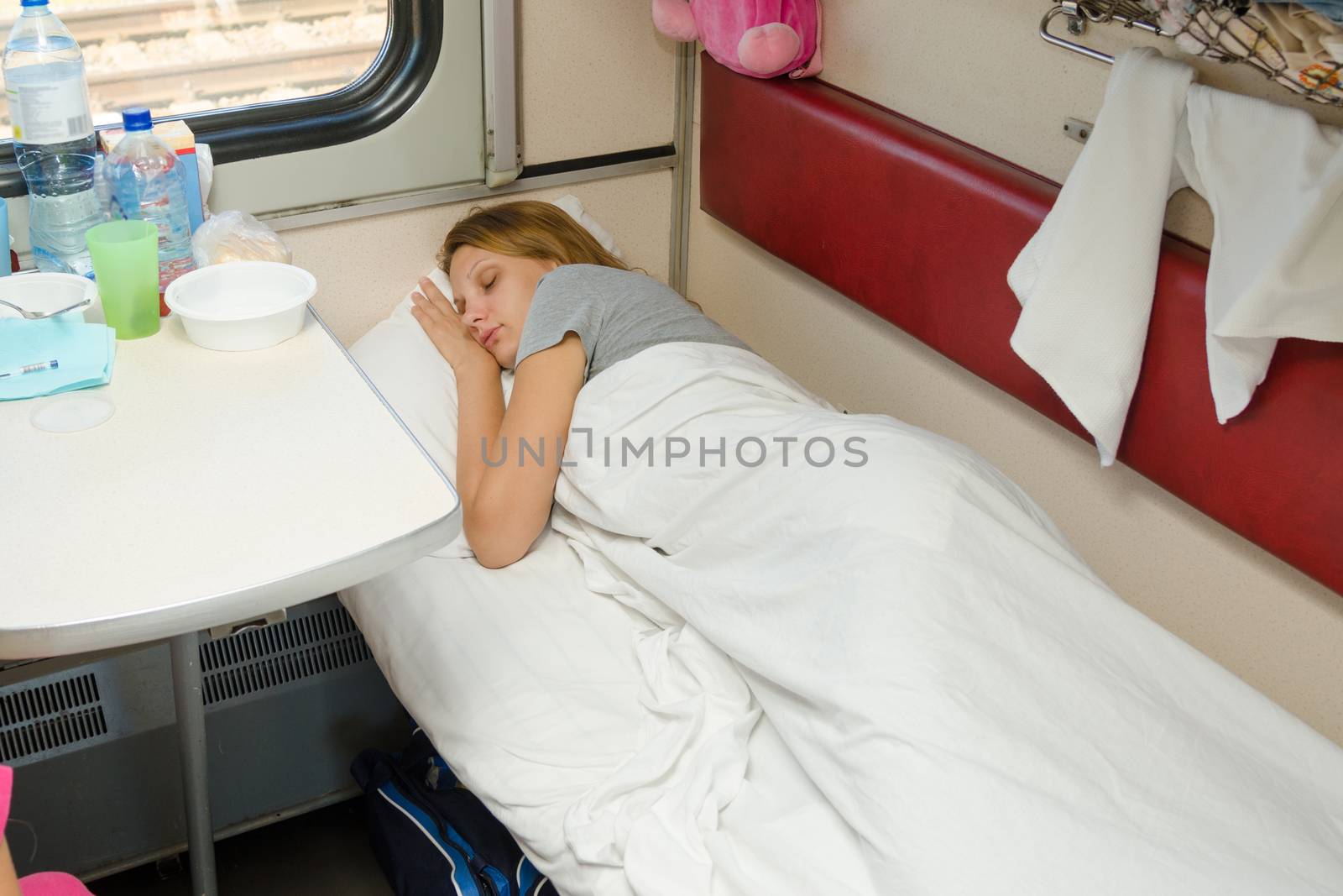 Girl sleeping in a train compartment on the lower second-class place car