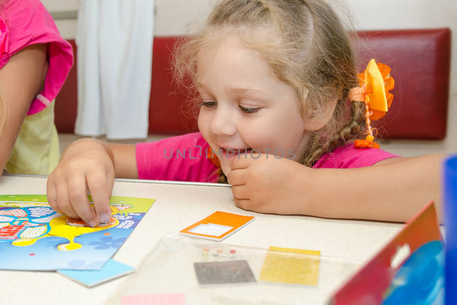 Four-year girl on a train sitting at the table on the lower second-class place car and enthusiastically plays